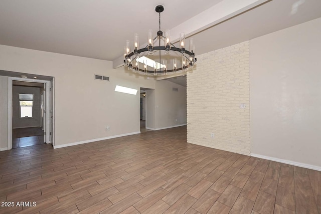 empty room featuring wood finished floors, visible vents, brick wall, baseboards, and beam ceiling