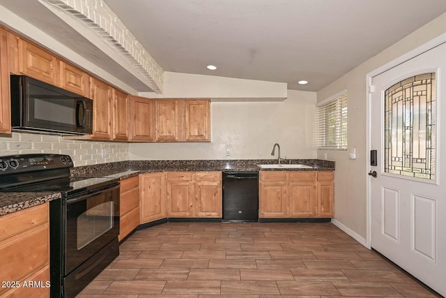 kitchen featuring black appliances, dark stone counters, recessed lighting, and a sink