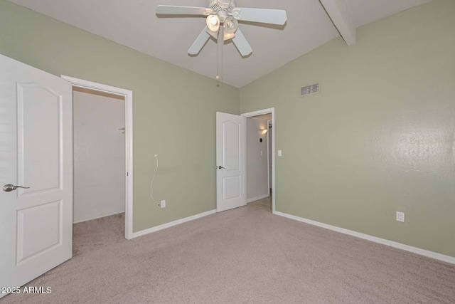 unfurnished bedroom with baseboards, light carpet, a spacious closet, and vaulted ceiling with beams