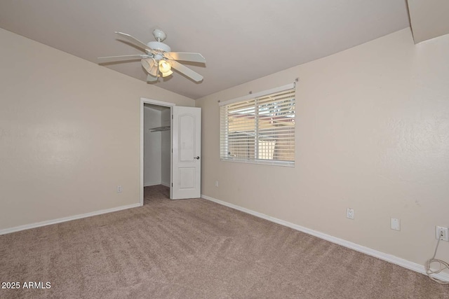 unfurnished bedroom featuring a ceiling fan, baseboards, carpet floors, lofted ceiling, and a spacious closet