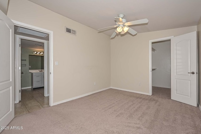 unfurnished bedroom with visible vents, carpet flooring, a walk in closet, and baseboards