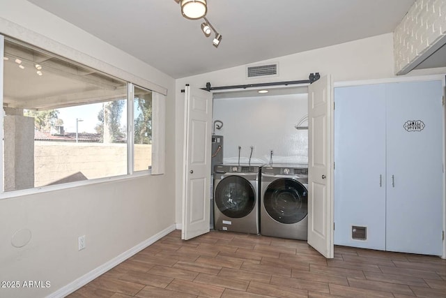 laundry area with visible vents, washer and clothes dryer, laundry area, baseboards, and wood tiled floor