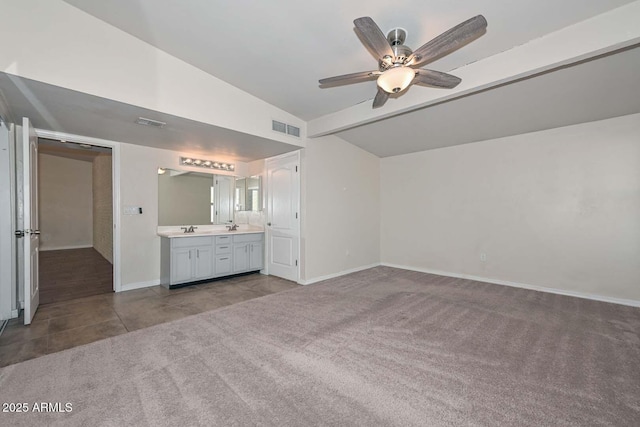 unfurnished bedroom featuring baseboards, visible vents, dark carpet, and a sink