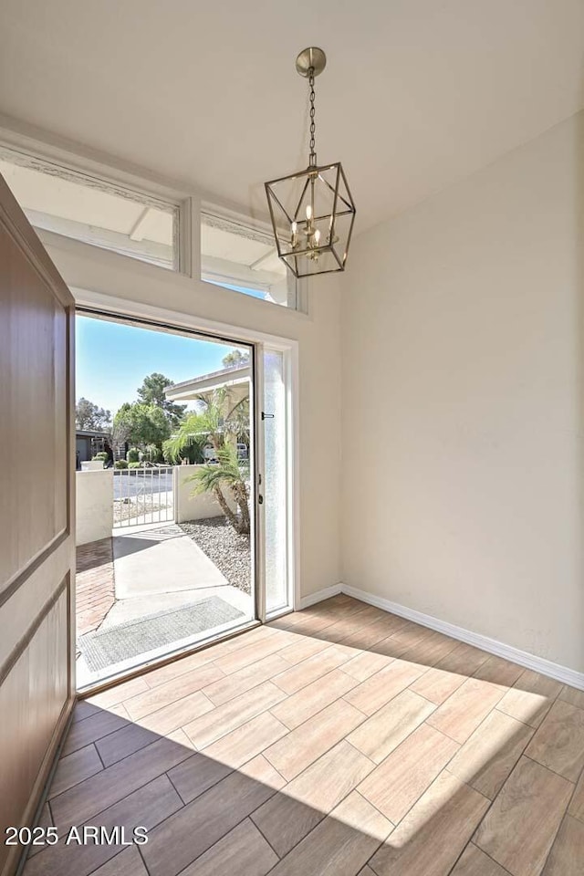 doorway with wood finish floors, baseboards, and a chandelier