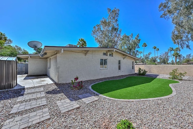 rear view of property with a patio area, a fenced backyard, an outdoor structure, and stucco siding