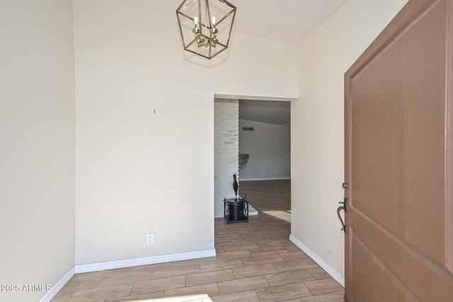 unfurnished room with baseboards, an inviting chandelier, and wood tiled floor