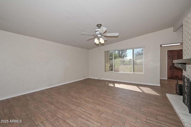 unfurnished living room with a brick fireplace, baseboards, vaulted ceiling, wood finished floors, and a ceiling fan