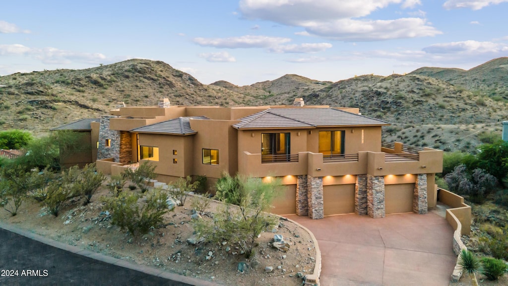 pueblo-style home featuring a mountain view, a garage, and a balcony