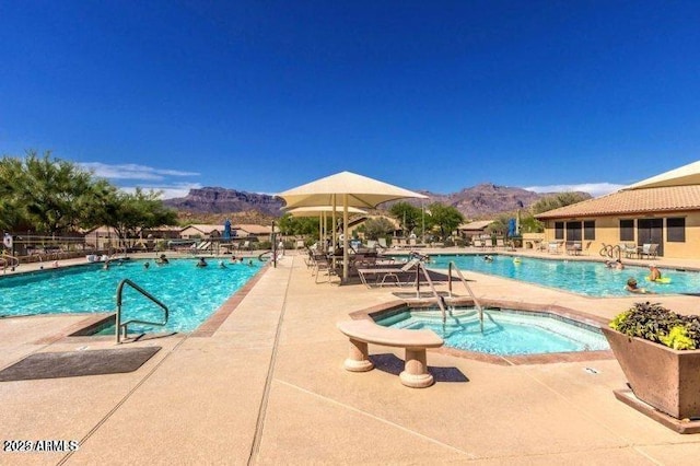 view of pool featuring a mountain view, a patio area, and a hot tub