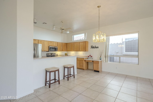 kitchen featuring ceiling fan, stainless steel appliances, light tile patterned flooring, decorative light fixtures, and kitchen peninsula