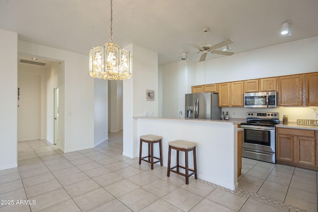 kitchen with a breakfast bar, hanging light fixtures, light tile patterned floors, stainless steel appliances, and ceiling fan with notable chandelier