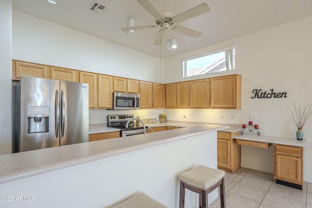 kitchen featuring light tile patterned flooring, appliances with stainless steel finishes, a kitchen breakfast bar, a high ceiling, and ceiling fan