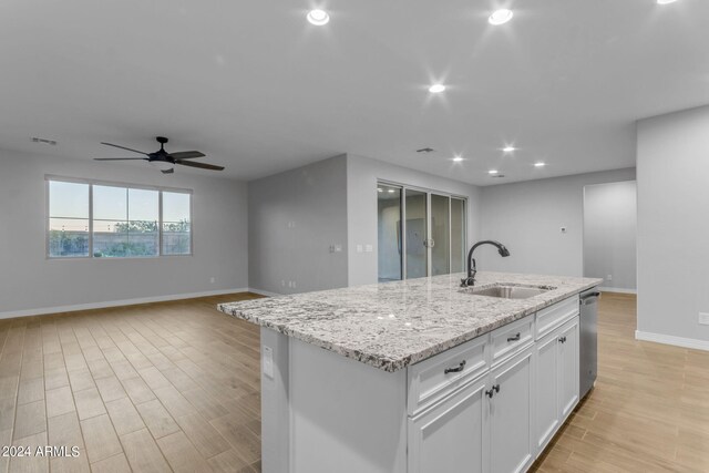 kitchen with gas stove, light stone counters, light wood-style floors, and white cabinets