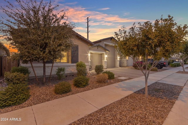 view of front of property featuring stucco siding, driveway, an attached garage, and fence