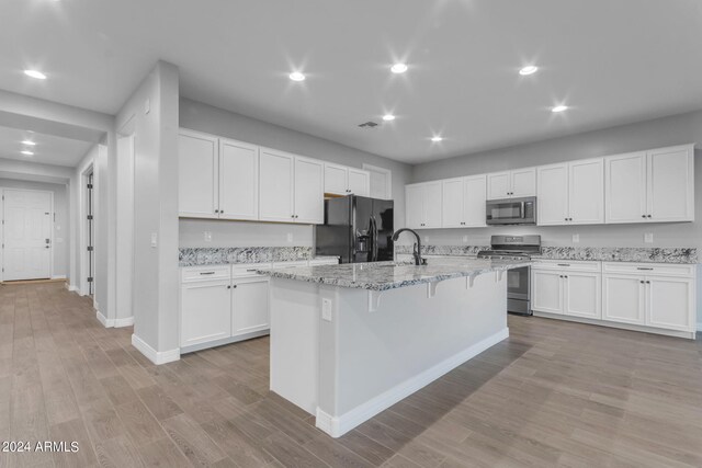 kitchen with stainless steel appliances, white cabinets, and light wood-style flooring