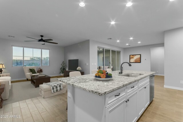 kitchen featuring visible vents, light wood-style flooring, a sink, stainless steel dishwasher, and white cabinets