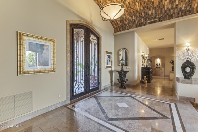 13249 E Summit Dr, Scottsdale, AZ 85259 - foyer entrance featuring arched walkways, baseboards, french doors, inlaid floor details, and a towering ceiling