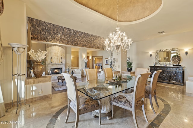 13249 E Summit Dr, Scottsdale, AZ 85259 - dining room featuring marble tiled floors, a lit fireplace, a chandelier, and inlaid floor details