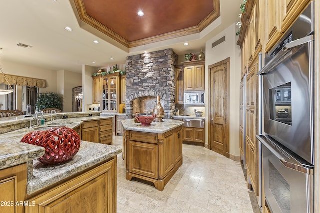 13249 E Summit Dr, Scottsdale, AZ 85259 - kitchen with a raised ceiling, appliances with stainless steel finishes, brown cabinets, a warming drawer, and a center island