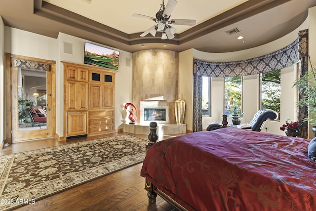 13249 E Summit Dr, Scottsdale, AZ 85259 - bedroom with a raised ceiling, hardwood / wood-style flooring, a tiled fireplace, recessed lighting, and a ceiling fan