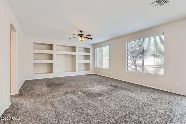 8766 W Hayward Ave, Glendale, AZ 85305 - unfurnished living room with a ceiling fan, baseboards, carpet, built in shelves, and arched walkways