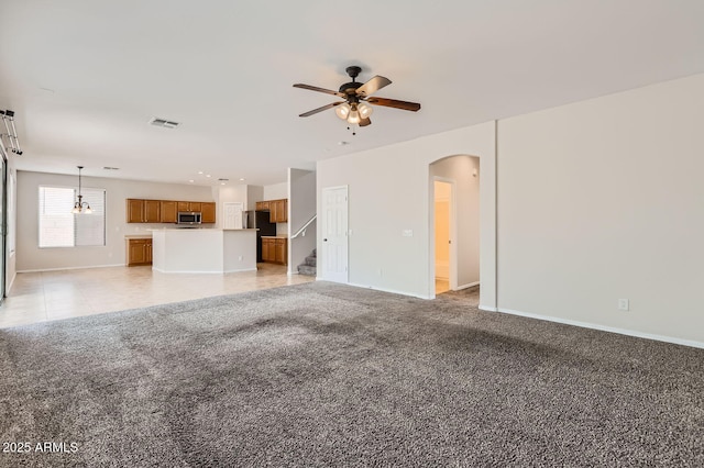 8766 W Hayward Ave, Glendale, AZ 85305 - unfurnished living room featuring baseboards, ceiling fan, arched walkways, and stairway