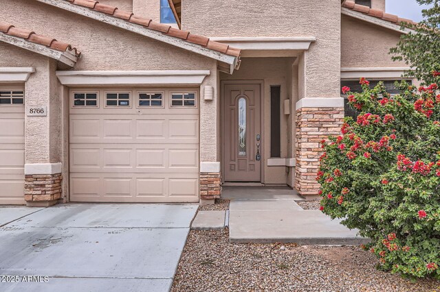 8766 W Hayward Ave, Glendale, AZ 85305 - entrance to property featuring stone siding, stucco siding, driveway, and a garage