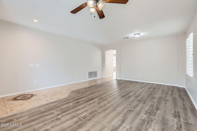 8766 W Hayward Ave, Glendale, AZ 85305 - unfurnished living room featuring wood finished floors, ceiling fan, arched walkways, and baseboards