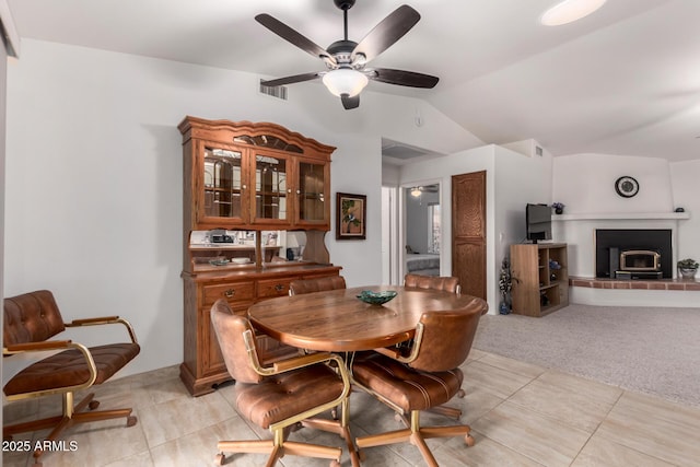 carpeted dining area with ceiling fan and vaulted ceiling