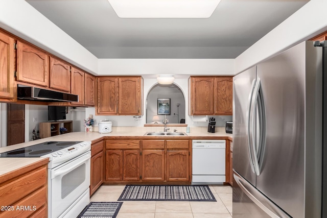 kitchen featuring white appliances, light tile patterned flooring, and sink