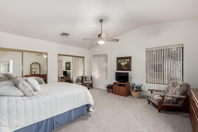 bedroom featuring ceiling fan, two closets, lofted ceiling, and carpet flooring