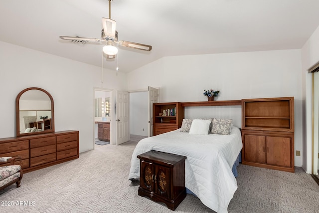 bedroom with lofted ceiling, ensuite bath, light colored carpet, and ceiling fan