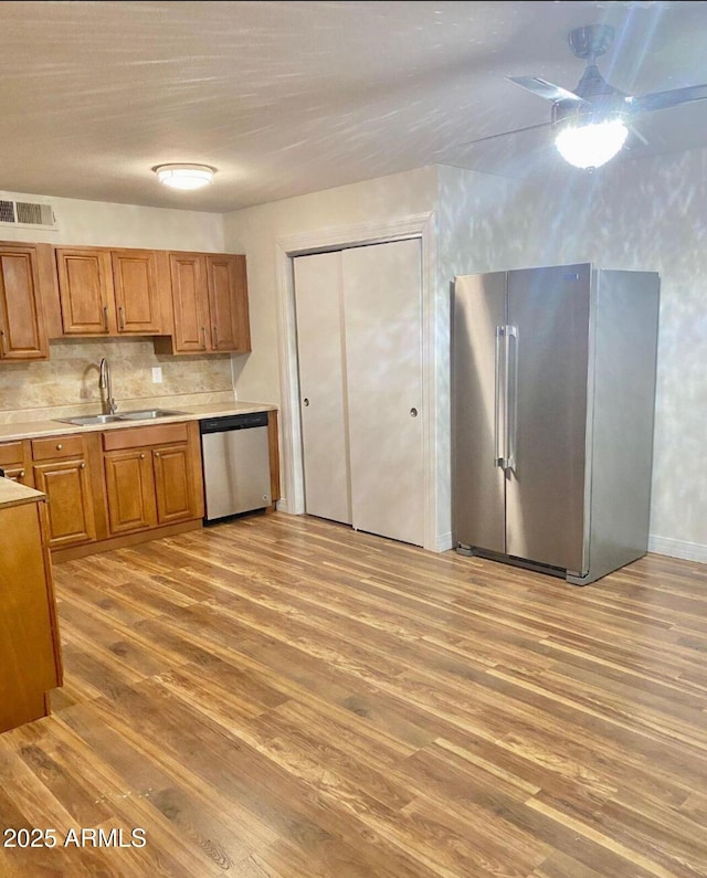 kitchen featuring light wood-type flooring, appliances with stainless steel finishes, decorative backsplash, and sink