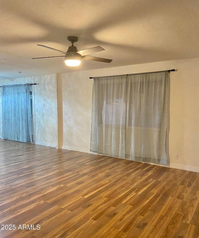 empty room with a textured ceiling, ceiling fan, and dark hardwood / wood-style flooring