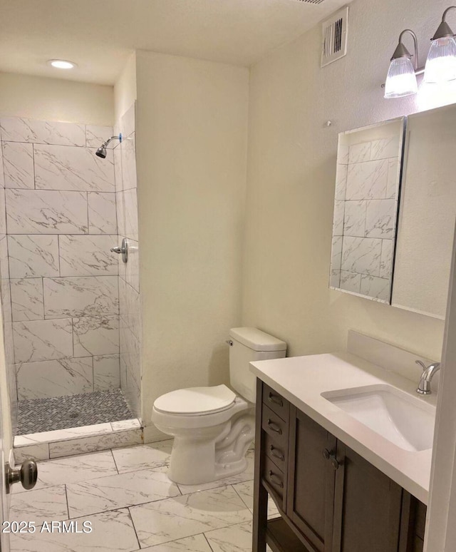 bathroom featuring toilet, vanity, and tiled shower