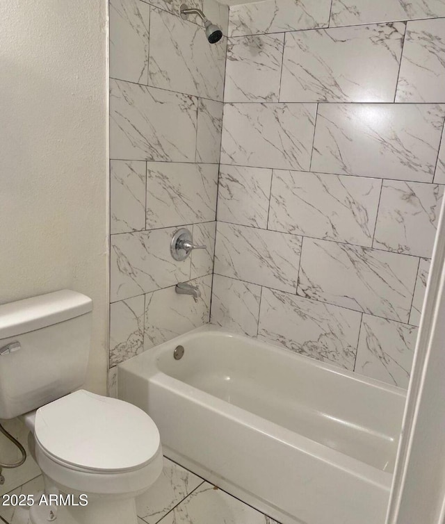 bathroom featuring toilet and tiled shower / bath