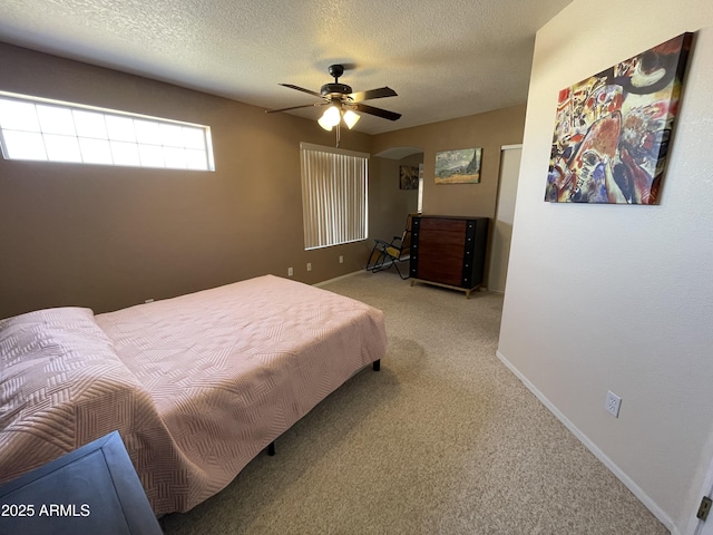 bedroom with ceiling fan, light carpet, and a textured ceiling