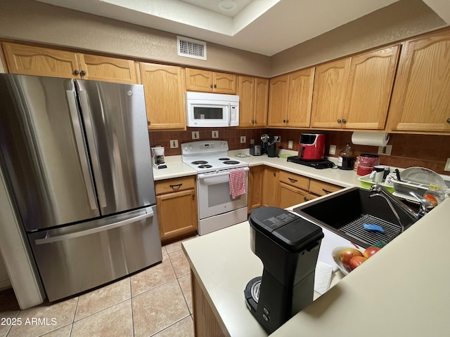 kitchen featuring light brown cabinetry, tasteful backsplash, sink, light tile patterned floors, and white appliances