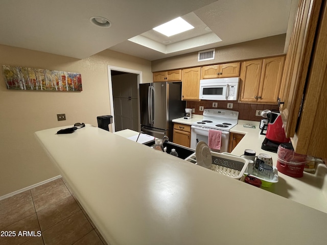 kitchen featuring kitchen peninsula, tile patterned floors, white appliances, and decorative backsplash