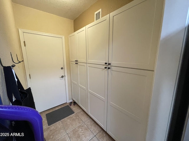 doorway to outside featuring light tile patterned flooring and a textured ceiling