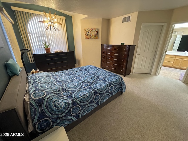 bedroom with ensuite bathroom, carpet floors, and a chandelier