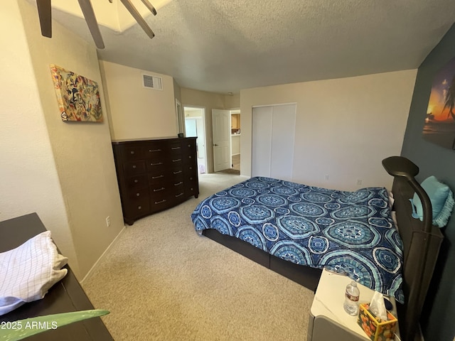 bedroom with ceiling fan, light colored carpet, and a textured ceiling