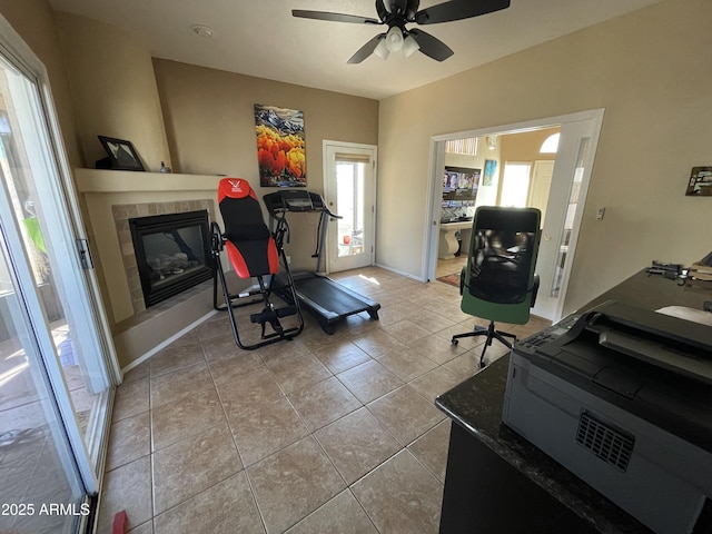 workout area with ceiling fan, a fireplace, and light tile patterned floors