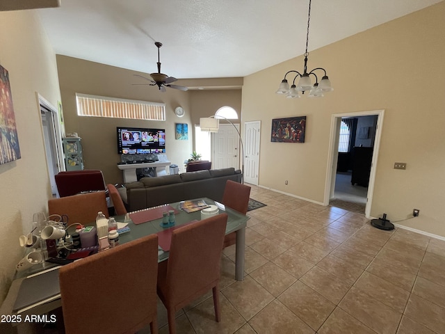 dining area featuring a wealth of natural light, a towering ceiling, ceiling fan with notable chandelier, and tile patterned floors