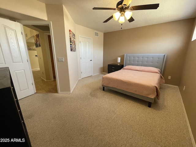 bedroom featuring ceiling fan, light carpet, and a textured ceiling