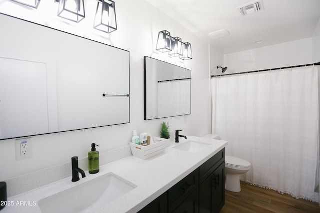 full bath featuring visible vents, a sink, toilet, and wood finished floors