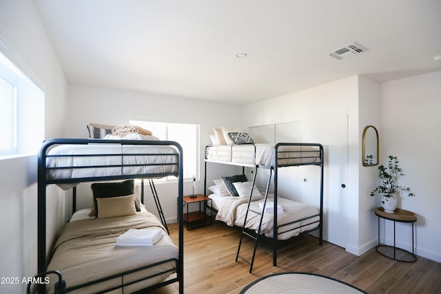 bedroom featuring baseboards, visible vents, and wood finished floors