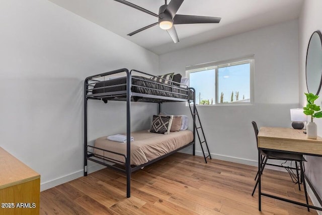 bedroom featuring baseboards, wood finished floors, and a ceiling fan