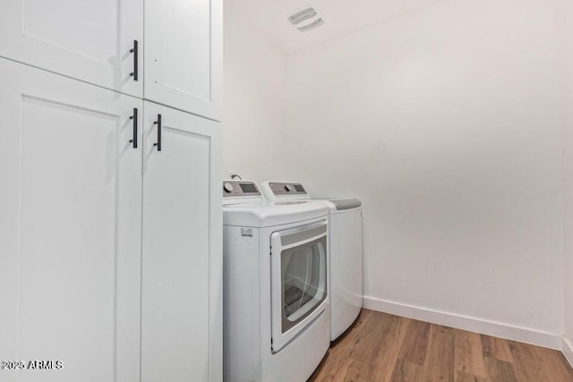washroom with independent washer and dryer, baseboards, light wood-style floors, visible vents, and cabinet space