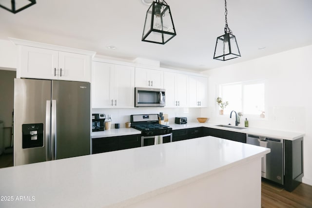 kitchen featuring light countertops, a sink, stainless steel appliances, and decorative light fixtures